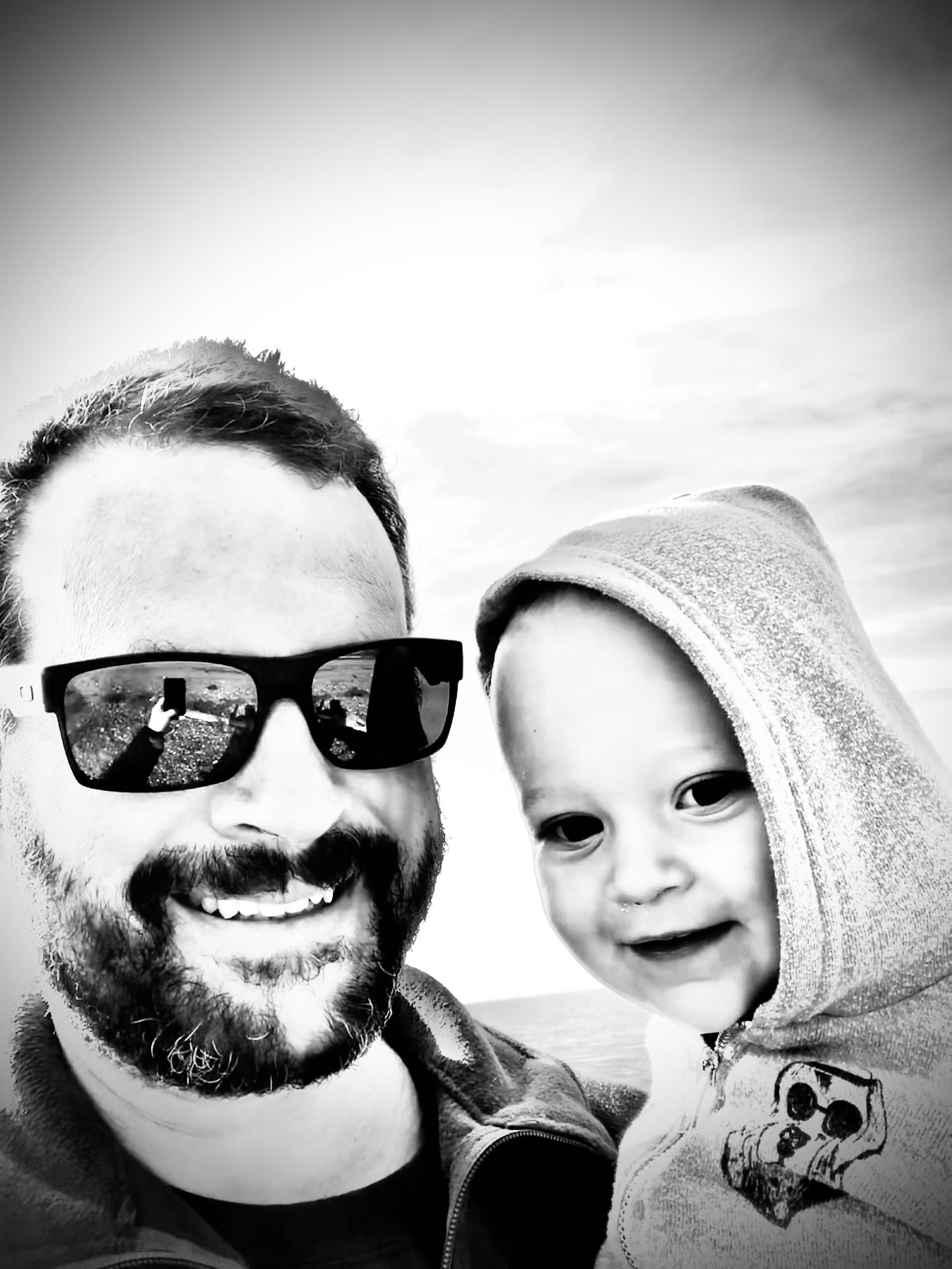 Black-and-white photo of a father and his young son by the water